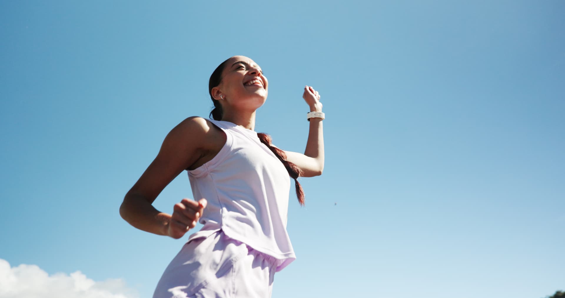 Woman running outdoors beneath an open blue sky