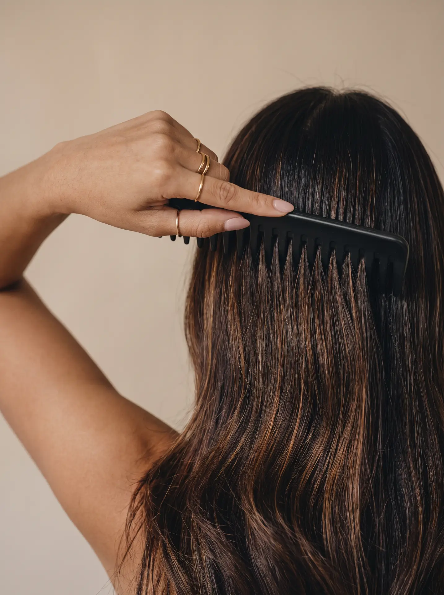 A hand combing dark hair with a wide black comb