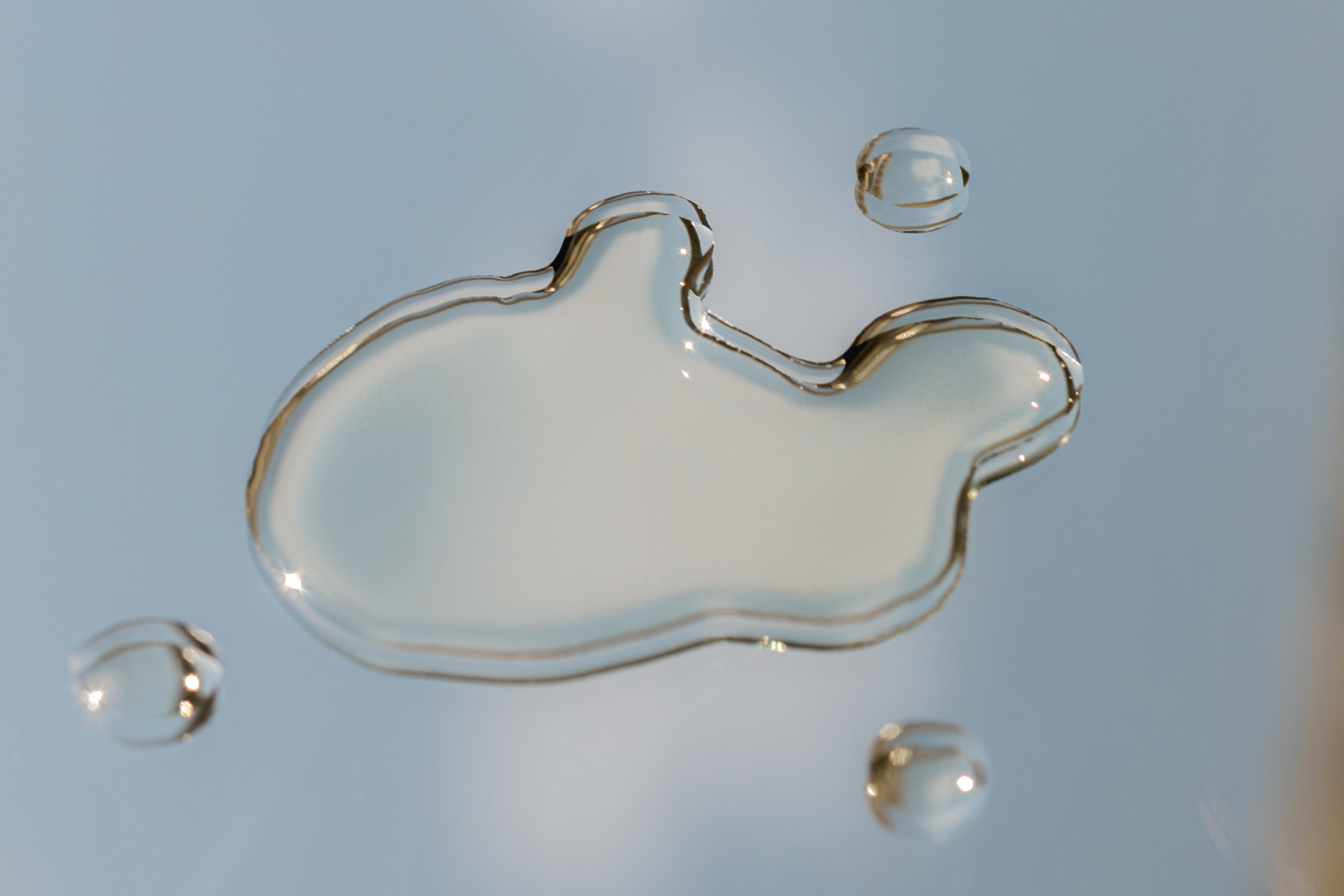 A stream of clear serum against a soft blue background
